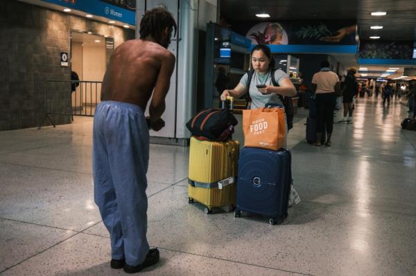 A homeless person co<em></em>nfronting a tourist at the train station.