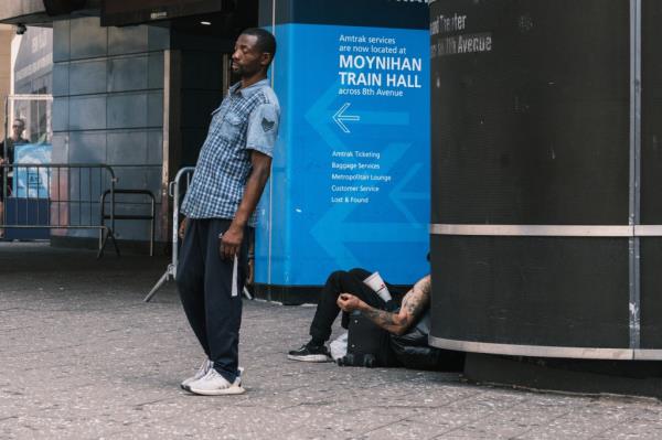 People sitting and standing near the entrance to the Moynihan Train Hall.