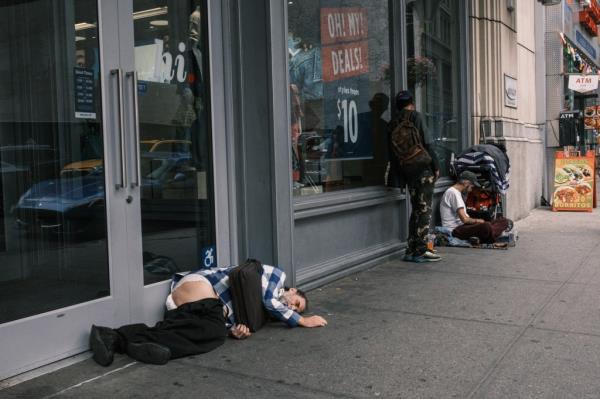 People sleeping on the ground near the entrance to a business in Manhattan by Penn Station.