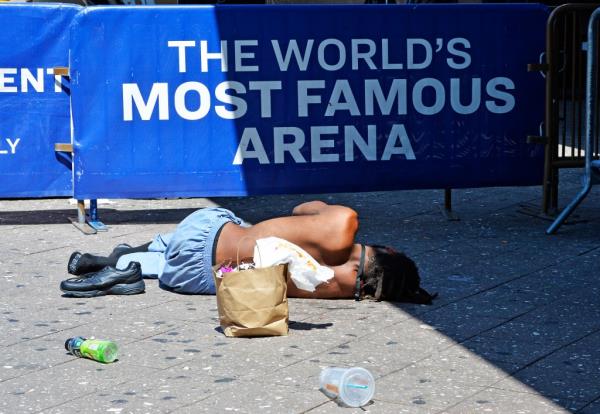 A homeless man on the ground next to a sign for Madison Square Garden on Aug. 27, 2024.