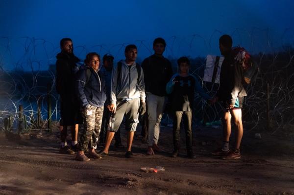 Migrants stand at the river bank of the Rio Grande to turn themselves into Border Patrol.