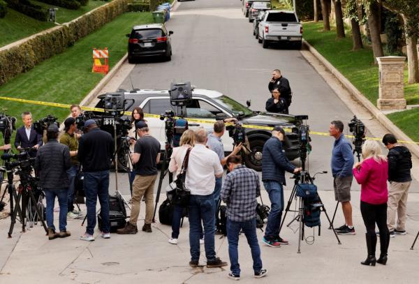 Media members work as law enforcement officers stand behind police tape outside a property co<em></em>nnected to hip-hop star Sean 