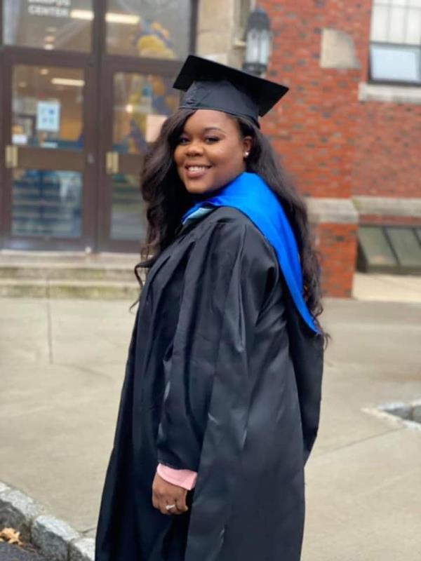 Alexis Breeden seen n cap and gown on graduation day outside of alma mater school