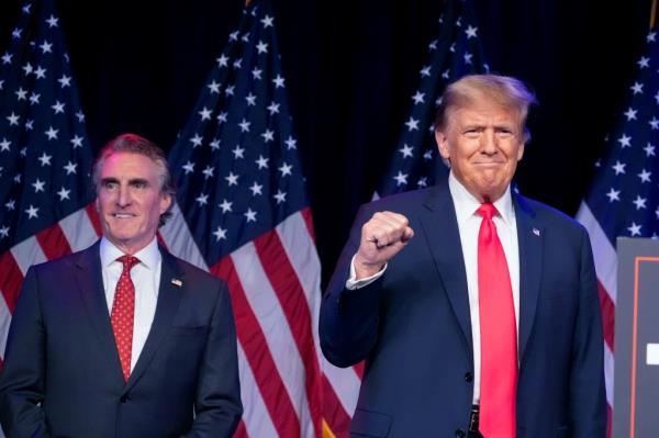 Do<em></em>nald Trump arrives to speak at a caucus night rally in Las Vegas, Feb. 8, 2024, as North Dakota Gov. Doug Burgum watches. 