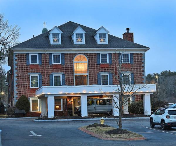 Former Comfort Inn in Rockland, now a shelter for immigrants, shown by a large brick building with a parking lot in Rockland, MA.