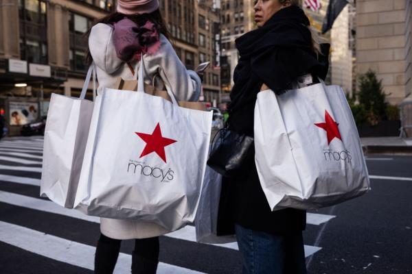 Two women carrying Macy's shopping bags during Black Friday sale in New York City.