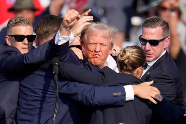 Trump pumps his fist as he is helped off the stage at a campaign event in Butler, Pa., on Saturday, July 13, 2024.