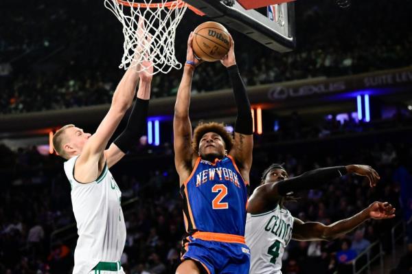 Miles McBride goes up for a shot as Kristaps Porzingis defends during the Knicks' 116-102 loss to the Celtics.