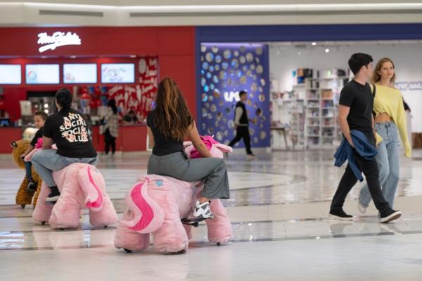 A photo of three people operating Dream Riders as a couple passes.