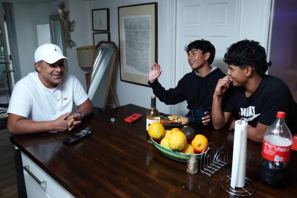 Venezuelan migrant Argenis Davila, from left, at home in Chicago with Elian Estrada, a migrant from Ecuador, and Estrada’s friend Adrian Davila, who is Argenis’ son, on Oct. 12, 2023.