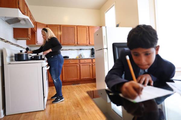 Venezuelan migrant Yohana Maria Moreno Mu?oz, 39, prepares dinner as her younger son, Isaac, 11, does homework at their apartment on Oct. 18, 2023. The family started renting the unit in August with help from the Chicago Low-Income Housing Trust Fund.