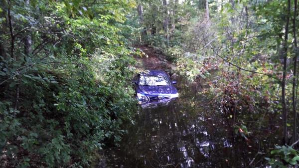 The car on the dirt road, partially submerged. 