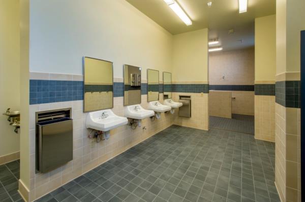 Men's restroom in a small seco<em></em>ndary school, featuring sinks, mirrors, and an attached shower room.