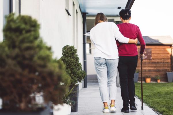 A caregiver helps an elderly lady.