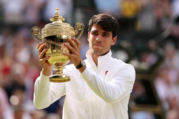 Carlos Alcaraz of Spain poses with the Gentlemen's Singles Trophy following victory against Novak Djokovic of Serbia in the Gentlemen's Singles Final during day fourteen of The Champio<em></em>nships Wimbledon.