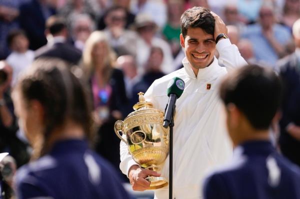 Carlos Alcaraz of Spain reacts as he is interviewed on court as he holds his trophy after defeating Novak Djokovic of Serbia in the men's singles final at the Wimbledon tennis champio<em></em>nships in London, Sunday, July 14, 2024. 