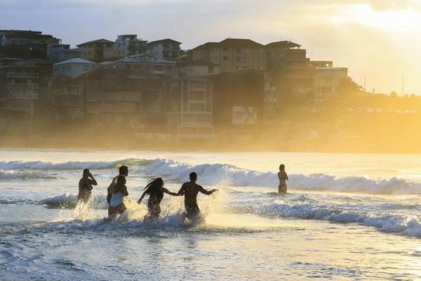 People run into the water as the sun rises at Bo<em></em>ndi Beach