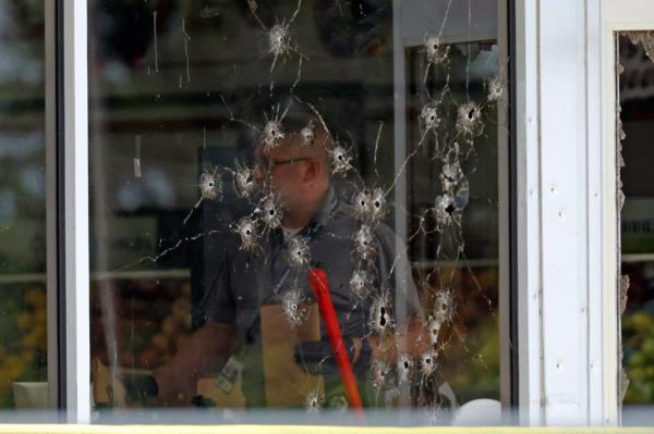 A front window is seen with bullet holes as law enforcement officers work the scene following the shooting on June 21 in Arkansas.