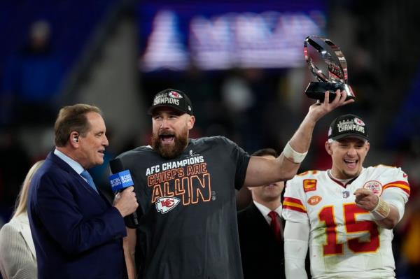 Travis Kelce holding a trophy, Patrick Mahomes stands beside him, after winning the AFC Champio<em></em>nship game between Chiefs and Ravens.