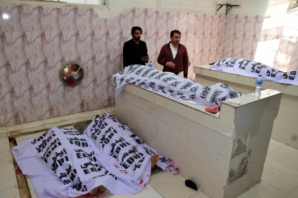 People stand by bodies of victims, as they try to identify them following Pashin district's bomb blast, at a morgue in a hospital in Quetta, Pakistan on Feb. 7, 2024.