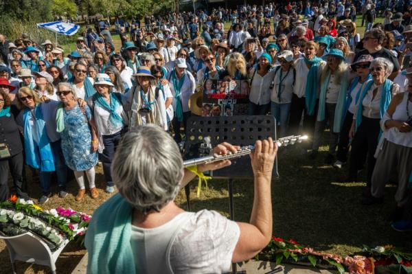 A woman plays a flute as members of 'Women Wage Peace' sing together at Silver's service.