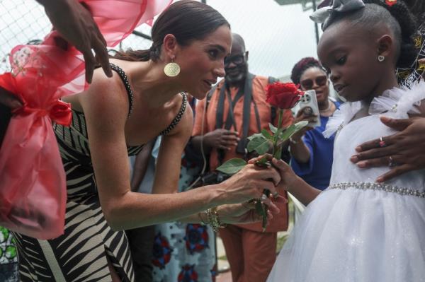 receives flowers from a girl upon her arrival with Britain's Prince Harry (unseen), Duke of Sussex, for an exhibition sitting volleyball match at Nigeria Unconquered, a local charity organisation that supports wounded, injured, or sick servicemembers, in Abuja on May 11, 2024 as they visit Nigeria as part of celebrations of Invictus Games anniversary.