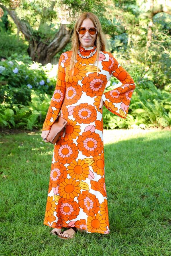 Dorit Bar Or wearing a long orange print dress.