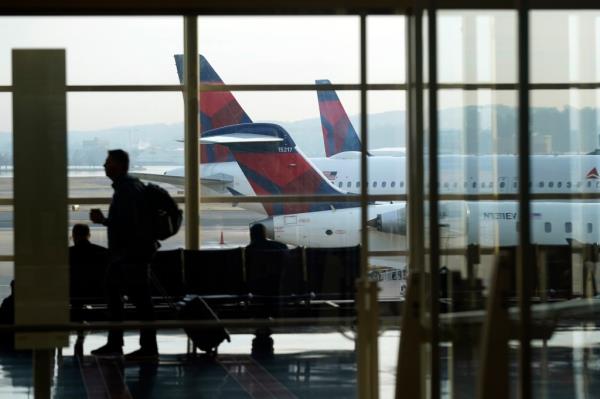 A person walks through the terminal as planes remain at gates at Ro<em></em>nald Reagan Washington Natio<em></em>nal Airport in Arlington, Va., Wednesday, Jan. 11, 2023.