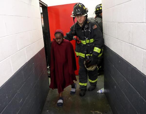 A FDNY firefighter leading a child out of the building during the January 2022 blaze.