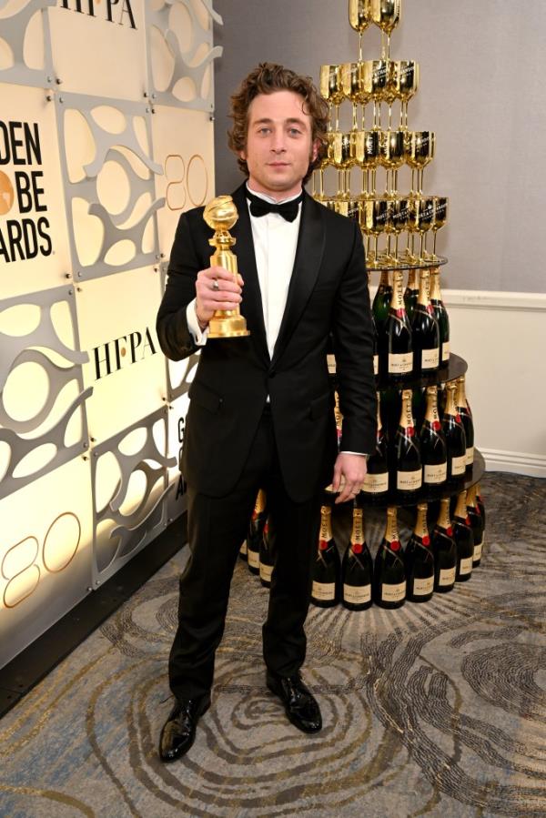 Jeremy Allen White holding a Golden Globe and standing in front of a Mo?t and Chandon tower.