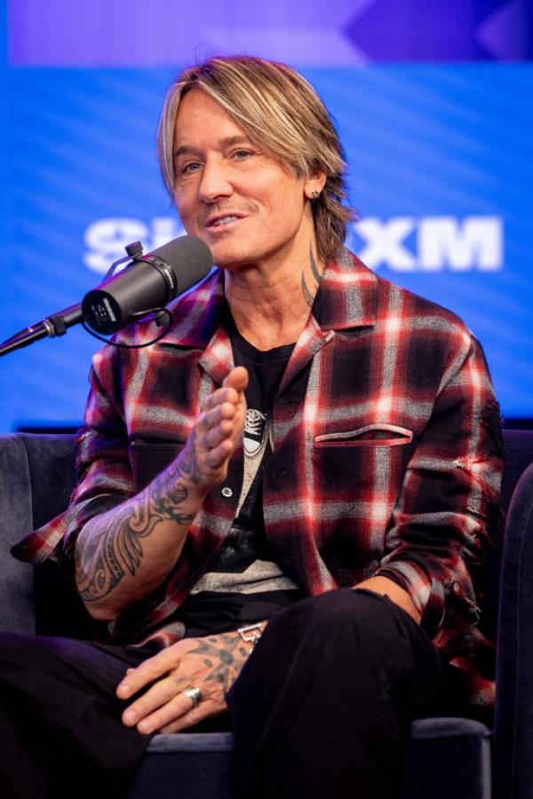 Keith Urban sitting in a chair with a microphone at a live taping of SiriusXM's 'Literally! With Rob Lowe' in Los Angeles, California