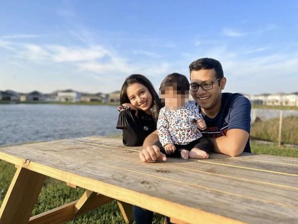 Abdullah is pictured with his wife and young daughter at a picnic table on the water.