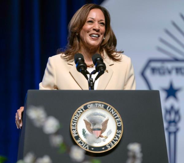 Vice President Kamala Harris speaking at the Zeta Phi Beta Sorority Co<em></em>nference in Indianapolis, standing at a podium with microphones.