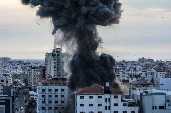 A plume of smoke rises from a building struck by an explosive in Israel. 