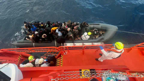 SALVAMENTO MARITIMO/REUTERS Spanish coast guards wearing white suits on a ship work on towing a rubber boat carrying migrants, including a newborn baby, off the island off the Canary Island of Lanzarote